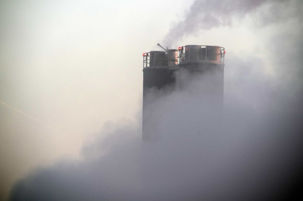 Imagem de uma chaminé industrial emanando gases poluentes.