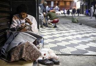 A homeless eats as he spends the night on the street in downtown Sao Paulo, Brazil, on June 26, 2016. - Earlier this month six homeless people died of cold in Sao Paulo, the richest city in Brazil, where some 16,000 homeless live on the streets. (Photo by Miguel Schincariol / AFP) / TO GO WITH AFP STORY BY ROSA SULLEIRO