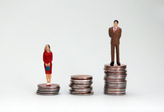 Gender wage difference concept. A miniature woman standing on a pile of low coins and a miniature man standing on top of a pile of tall coins.