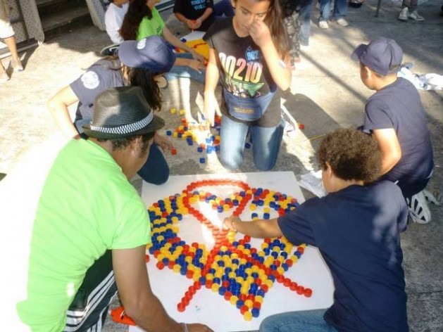 Um grupo de crianças cria com algumas tampinhas o laço que simboliza a luta contra a aids, em uma das atividades que se repetem na América Latina para conscientizar a população sobre a doença. Foto: Onusida América Latina