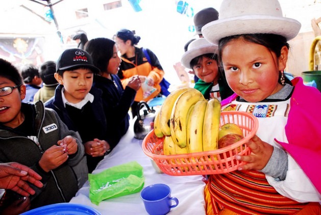 Usando roupa tradicional e festiva da zona andina da Bolívia, menina mostra, durante uma feira em sua escola no centro de La Paz, uma cesta de frutas, que são a base da nova dieta escolar adotada no município, que privilegia alimentos naturais, andinos e fornecidos por pequenos produtores locais. A aliança da agricultura familiar com a alimentação escolar se estende pela América Latina graças a leis impulsionadas pela Frente Parlamentar Contra a Fome. Foto: Franz Chávez/IPS