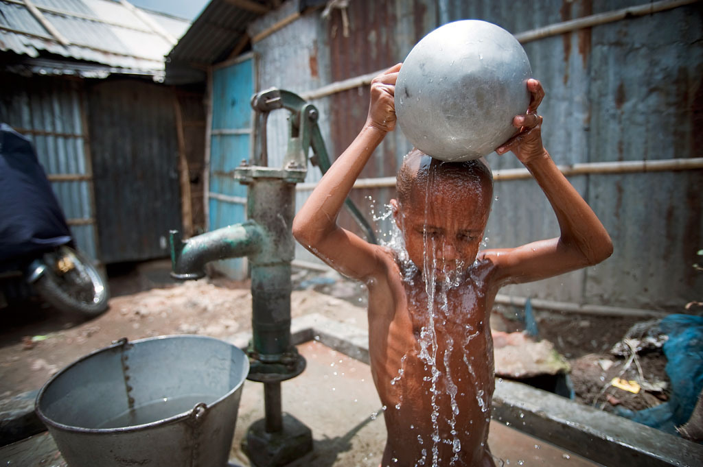 Jovem se lava em Kallyanpur, bairro pobre na capital de Bangladesh. Foto: ONU / Kibae Park