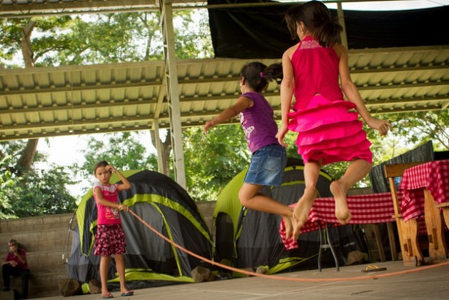 Meninas pulam corda no abrigo onde elas e suas famílias permanecem refugiadas na localidade de Caluco, no ocidente de El Salvador, em uma instalação improvisada em uma quadra de basquetebol. Dezenas de famílias fugiram em massa da vizinha comunidade agrícola de El Castaño devido à violência e às ameaças de gangues. Foto: Edgardo Ayala/IPS