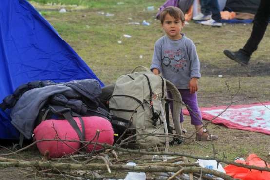 Menino afegão mostra os pertences de sua família em frente a uma barraca de campanha, perto de Röszke, na Hungria. Foto: Zsolt Balla/© Alto Comissariado para os Refugiados