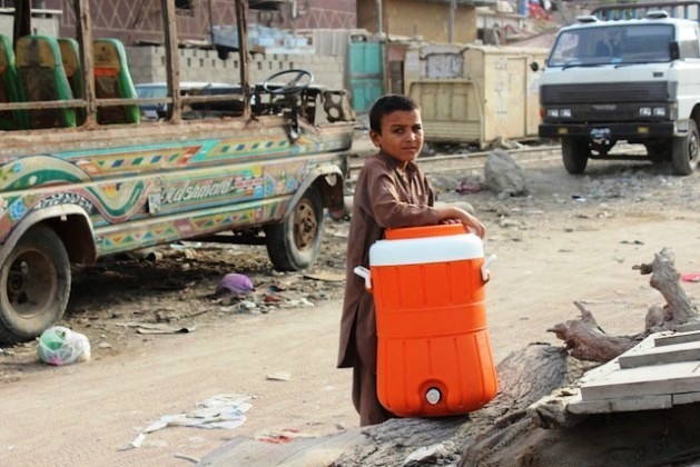 Um menino de um assentamento informal em Karachi carrega um recipiente para recolher água nas torneiras de casas particulares, que os habitantes mais ricos colocam à disposição dos pobres como um ato de caridade. Foto: Zofeen T. Ebrahim/IPS