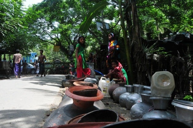 Dezenas de mulheres esperam na fila para encher centenas de recipientes com água em Bangladesh. Foto: Amantha Perera/IPS