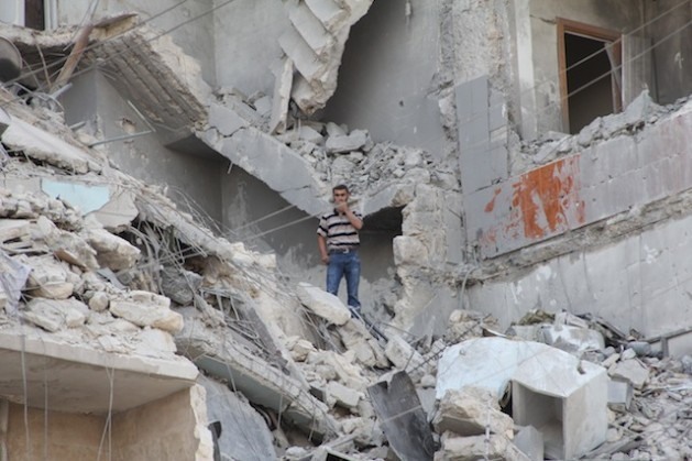 Residente da cidade síria de Aleppo em meio a um prédio bombardeado pelas forças do presidente Bashar al Assad. Foto: Zak Brophy/IPS