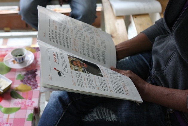 O jornalista eritreu folheia a revista que edita, Tsilal, que trata sobre os riscos da emigração e a difícil realidade de viver na Europa. Foto: James Jefrrey/IPS 