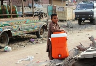 Um menino de um assentamento informal em Karachi carrega um recipiente para recolher água nas torneiras de casas particulares, que os habitantes mais ricos colocam à disposição dos pobres como um ato de caridade. Foto: Zofeen T. Ebrahim/IPS