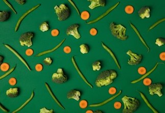 Colorful pattern of Broccoli, carrots and green beans on a green background. Top view of sliced seasonal vegetables. The concept of a healthy diet